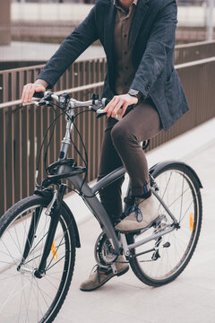 Unrecognizable contemporary stylish businessman going to work by bike