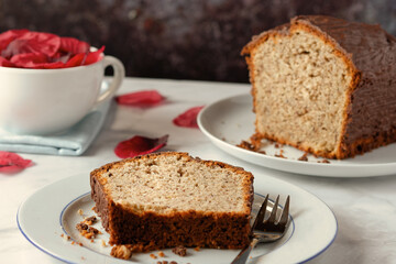 Homemade nut cake with chocolate icing served on a white plate.