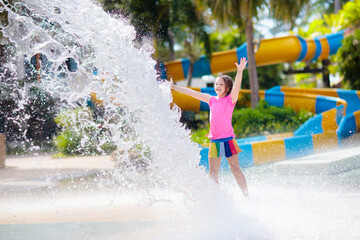 Child playing under tip bucket in water park.