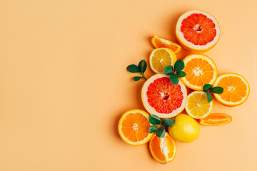 top view of orange grapefour and lemon citrus fruits with  herbs on peach  background