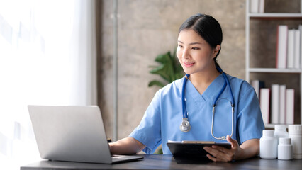 Asian female doctor sitting in office and holding patient file folder.