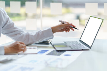 Businesswoman working using laptop computer to record and type data.