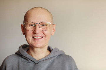 Smiling bald woman in glasses struggle with oncology look at camera. Hairless cancer sick female patient after chemotherapy lost her eyebrows and eyelashes feel optimistic of recovery remission - obrazy, fototapety, plakaty