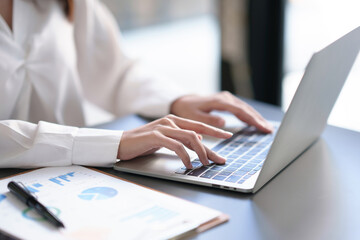 Businesswoman working using laptop computer to record and type data.