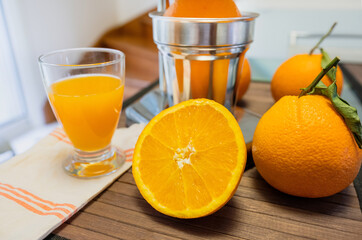 Beautiful close up of a chrome juicer with leafy oranges and juice