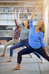 Reaching for their goals. Full length shot of three businesswomen doing yoga in the office.