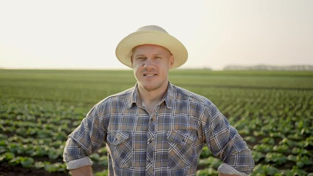 Portrait of young caucasian male farmer man worker with hat growing organic nutrition fresh vegetables looking at camera sunset spring field outdoor. Close up Concept harvest farming agriculture farm 