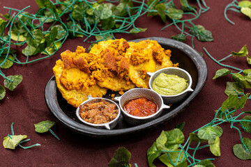 A plate of food with three small banana patacon of food on a table and salsas. Vegan food