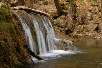 Waterfall in the forest surrounded by trees covered with moss