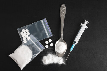 Hard Illegal drugs on dark background, cocaine or heroin white powder, white pills, syringe and...