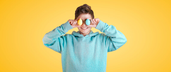 happy cute boy holding colorful easter eggs in front of her eyes. Banner for celebrating the joy of spring and the holiday season, perfect for Easter themed projects and designs. Copy space for text