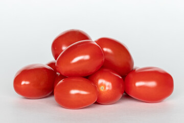 Pile of red small cherry tomatoes on white background, close up