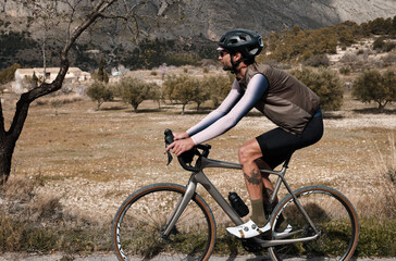 Fototapeta na wymiar A man on a gravel bike is riding on the road in the hills with a view of the mountains.Sport motivation.Alicante region in Spain
