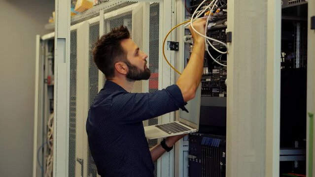 IT administrator repairing network switch in server room.