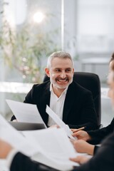 Smiling middle-aged businessman during a business meeting. The director of the company holds a meeting in the office.