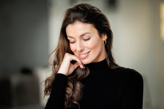 Close-up portrait of a brunette haired woman cheerful smiling and closing her eyes inside