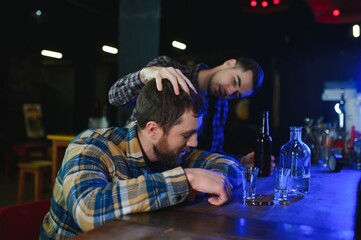 It was a hard day. Depressed young man drinking vodka in bar