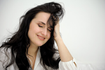 Fototapeta premium tenderness and beauty mind and strength beautiful brunette closes her eyes smiling on a white background in white sheets clean bed delicate skin advertising shampoos hair creams face creams toothpaste