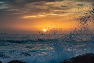Sea water splashing on the rocks at sunset, Porto - Portugal