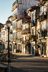 Fototapeta premium Vertical shot of golden sunset light over building facades at Cordoaria Square in Porto, Portugal