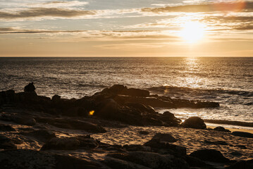 Golden sunset over the beach rocks in Porto, Portugal