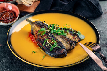 Grilled eggplant cut into pieces on a yellow plate. Vegan aubergine Dish, close up