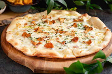 Pizza with chanterelles, cheese and rosemary. Italian pizza with mushrooms and herbs cut on a wooden board. Selective focus - obrazy, fototapety, plakaty