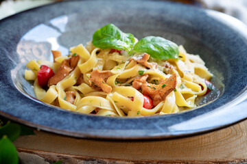 Pasta with chanterelles on a blue plate. Italian dish tagliatelle with mushrooms and parmesan cheese