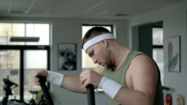 Strong middle-aged man is engaged in a simulator in the gym. Concept of sport and healthy lifestyle.