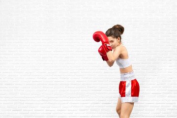 Attractive young woman in red boxing gloves and shorts stand in a boxing stance and protect her...