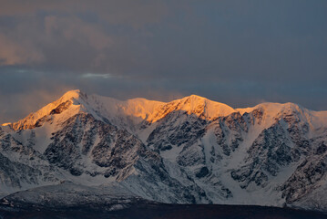 Russia. The South of Western Siberia, the Altai Mountains. The peaks of the North Chui mountain range illuminated by morning sunlight along the Chui tract near the village of Kurai.