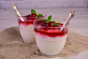 Rice pudding with cherry jam on a white wooden background.
