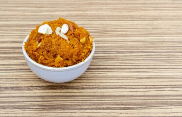 Authentic Homemade Gaja Ka Halva or Carrot Halwa Garnished with Cashew and Almond Nut Cuts Isolate on  Wooden Background with Copy Space