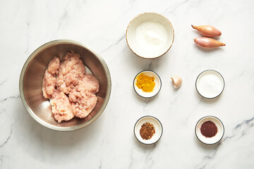 Chichen Persian Koobideh Kebab ingredients top view chicken and yogurt with turmeric, chilli flakes plus shallot, salt with sumac and garlic