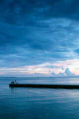 Obraz premium paisaje de atardecer en la costa con una entrada de tierra en el mar y el cielo azulado y violeta