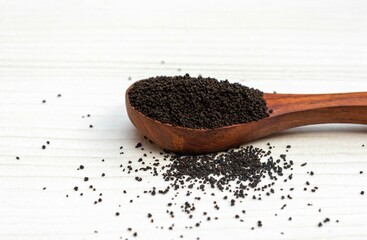 Dry Camellia Sinensis Leaves or Tea Leaves in a Wooden Spoon Isloated on White Wooden Background with Copy Space