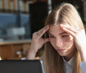 The girl looks thoughtfully at the laptop monitor. Online work. Distance learning.