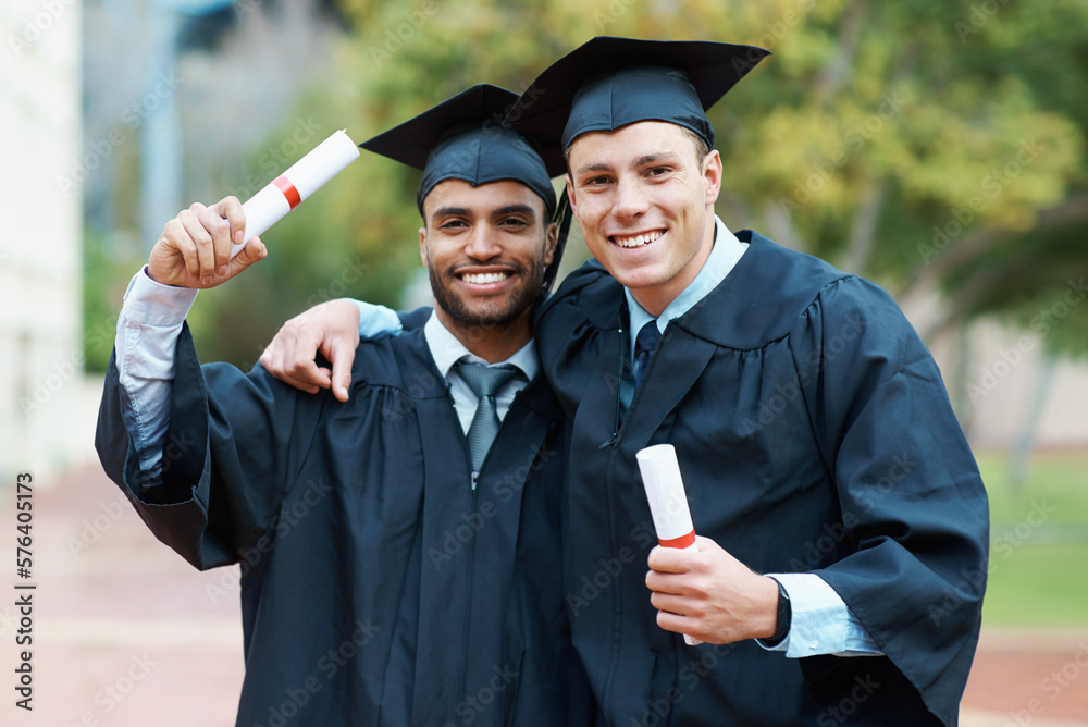 Wall mural Were on our way to success. Two young college graduates holding their diplomas while wearing cap and gown.