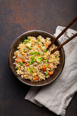 Authentic Chinese and Asian fried rice with egg and vegetables in ceramic brown bowl top view on...