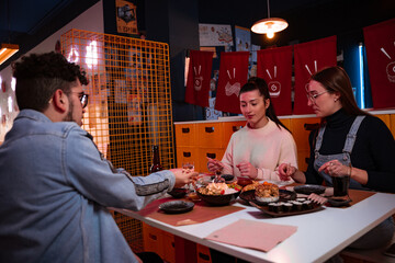 Friends of European origin enjoy eating sushi and Japanese food at a nice Japanese restaurant.