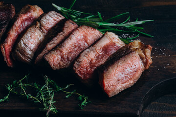 Grilled beef chuck roll steaks on wooden background with rosemary and thyme