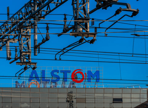 Savigliano; Cuneo; Italy - February 16; 2023: ALSTOM sign on the Savigliano factory; foreground railway power cables. ALSTOM is the world's leading factory producing trains and high-speed train