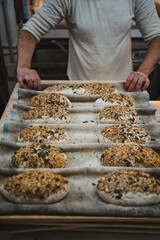 Professional baker folding couche cloth with seeds bread doughs on it