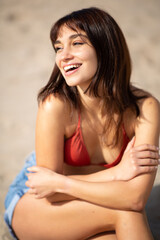 Fototapeta na wymiar Happy young woman sitting on sandy beach