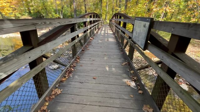 Walking over a wooden bridge over a small creek in the autumn