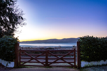 Colourful sunrise at the countryside with frosty fence and misty background