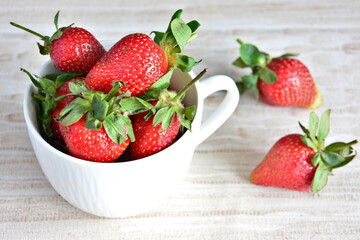 A white mug with garden strawberries isolated on pastel background, macro  