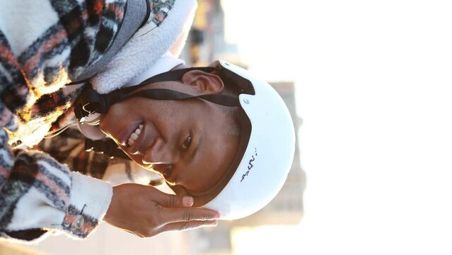 Latino Hispanic man relaxing after rollerblading in the city park, he takes off his helmet and looks at the camera. High quality 4k vertical recording