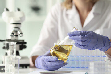 Scientist woman holding sample with yellow liquid