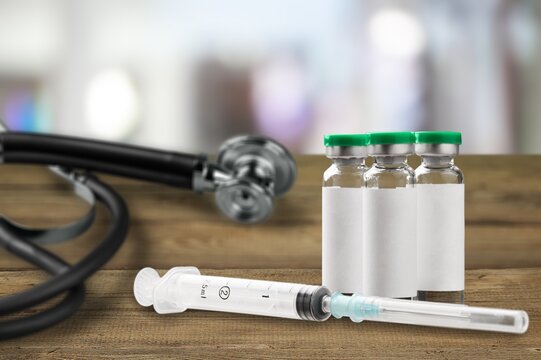 Bottles of medical vaccine vials with stethoscope on desk